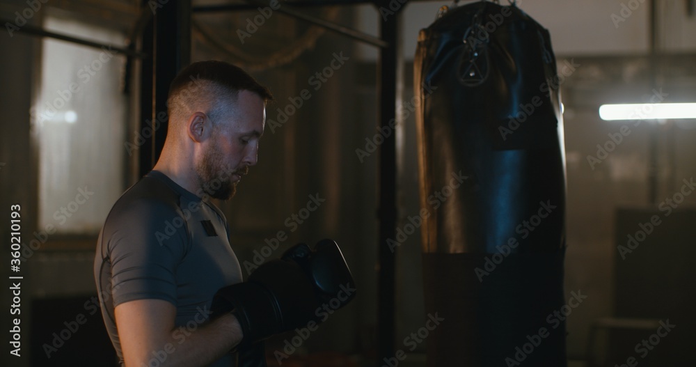 MS Caucasian male puts on boxing gloves in a boxing studio before training