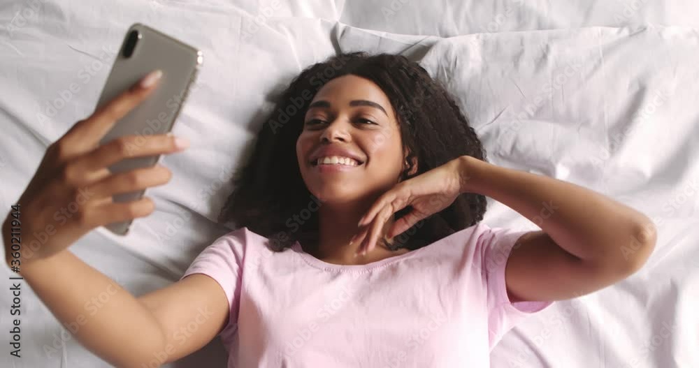 Pretty african american girl making selfie on cell phone in bed Pretty african american girl making selfie on cell phone in bed