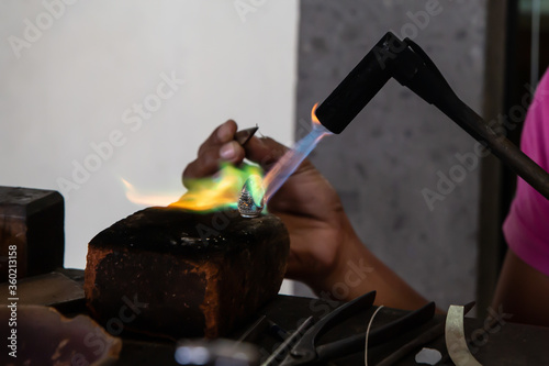 Tableau sur toile Balinese woman handcrafting a silver ring with a blow torch, Bali, Indonesia