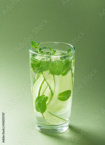  Fresh cold water with cucumber and mint on green background. Detox drink