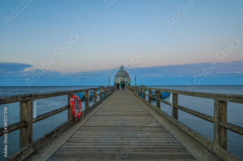 Pier on the Baltic Sea in the evening. Wooden jetty with a lifebuoy on the site and diving bell at the end. Evening horizon with clouds and calm sea on the island of Ruegen