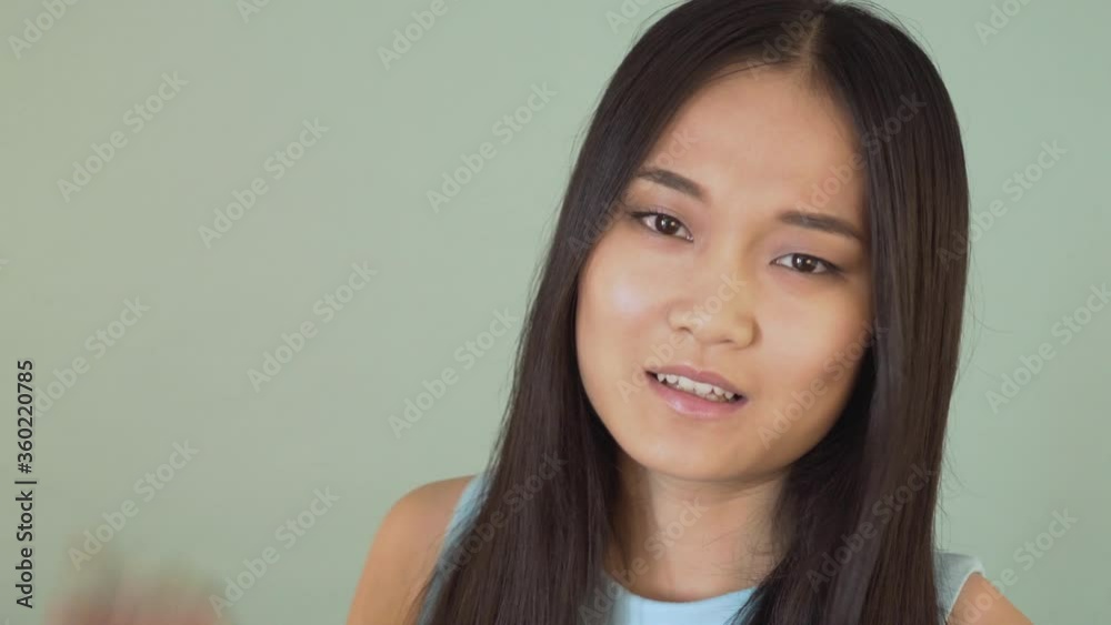 A sarcastic Asian girl annoyingly says blah blah blah and makes the same hand gesture. False information. . video blue isolated background. 4K A sarcastic Asian girl annoyingly says blah blah blah and makes the same hand gesture. False information. . video blue isolated background. 4K