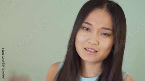 A sarcastic Asian girl annoyingly says blah blah blah and makes the same hand gesture. False information. . video blue isolated background. 4K photo