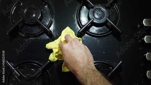 Close up of man cleaning cooker at home kitchen.Cleaning a gas stove with kitchen utensils, household concepts, or hygiene and cleaning.	 photo