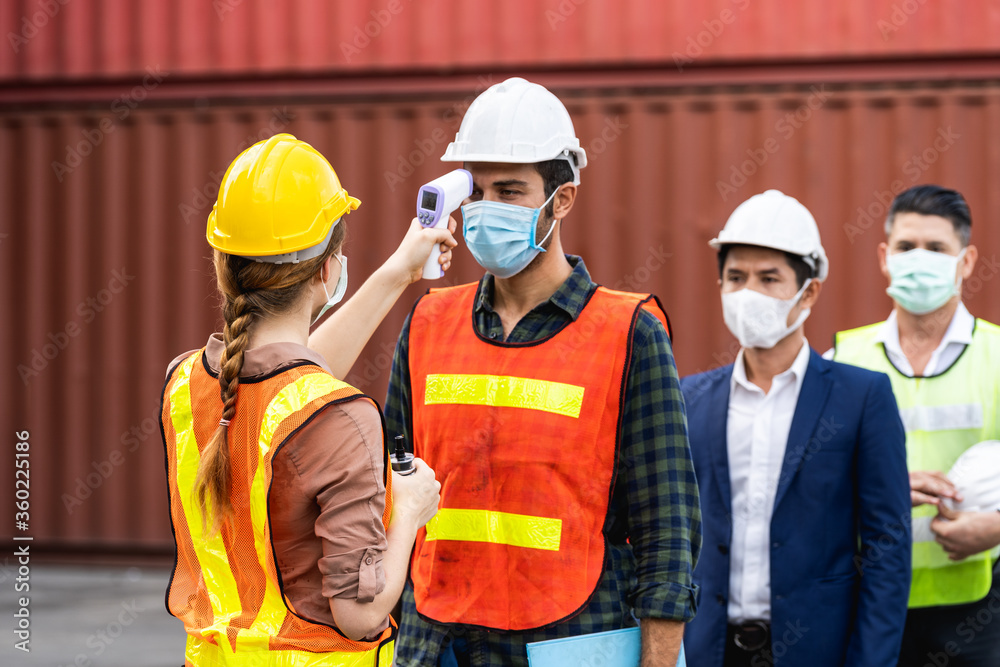 Engineer worker waring surgical mask checking body temperature using infrared digital thermometer check temperature before into work place, workers with protective mask Engineer worker waring surgical mask checking body temperature using infrared digital thermometer check temperature before into work place, workers with protective mask
