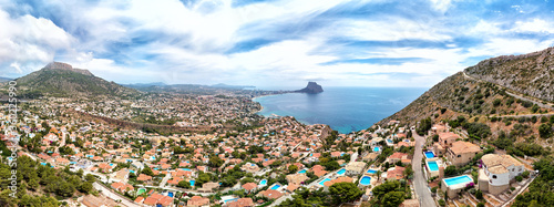 Aerial photography panoramic image Calpe or Calp townscape rooftops picturesque view to bright Mediterranean Sea waters and Parque natural Peñón de Ifach or Penyal de Ifac rock, Costa Blanca, Spain © Alex Tihonov