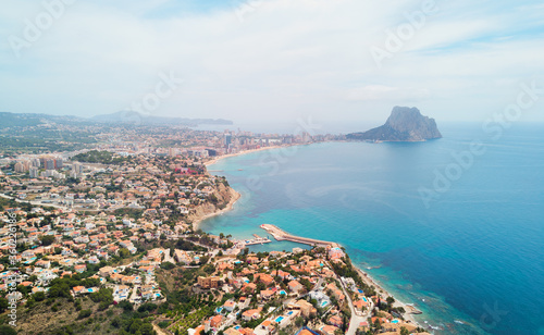 Aerial photography panoramic image Calpe or Calp townscape rooftops picturesque view bright Mediterranean Sea waters and Parque natural Penon de Ifach or Penyal de Ifac rock, Costa Blanca, Spain