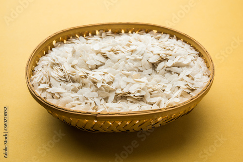 Raw Flattened Rice or Thick or thin Rice Flakes for Namkeen Chivda snacks or Aloo Poha for Indian Breakfast, served in a bowl photo