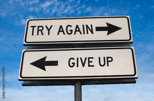 Try again vs give up. White two street signs with arrow on metal pole with word. Directional road. Crossroads Road Sign, Two Arrow. Blue sky background. Two way road sign with text.