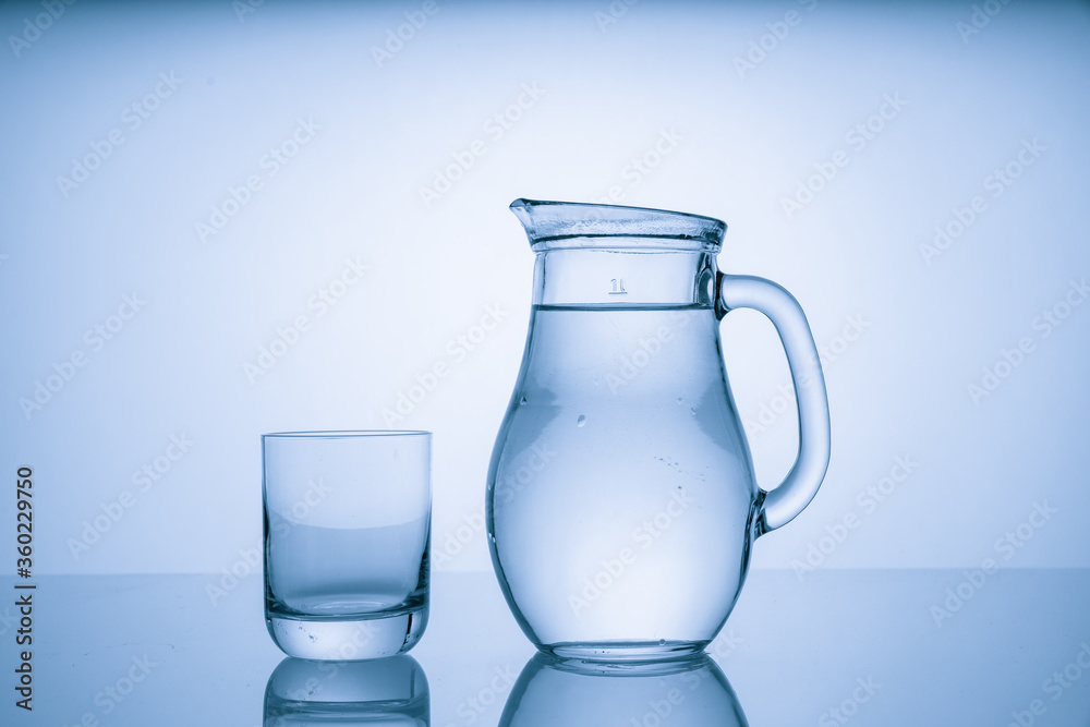 Pitcher with drinking water and a glass with a drink, blue tone Pitcher with drinking water and a glass with a drink, blue tone