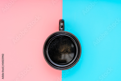 Cup of coffee on a gently pink and turquoise background. Top view flat lay.