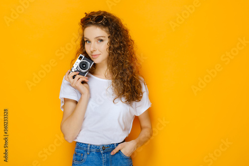 Beautiful photographer girl isolated on yellow background