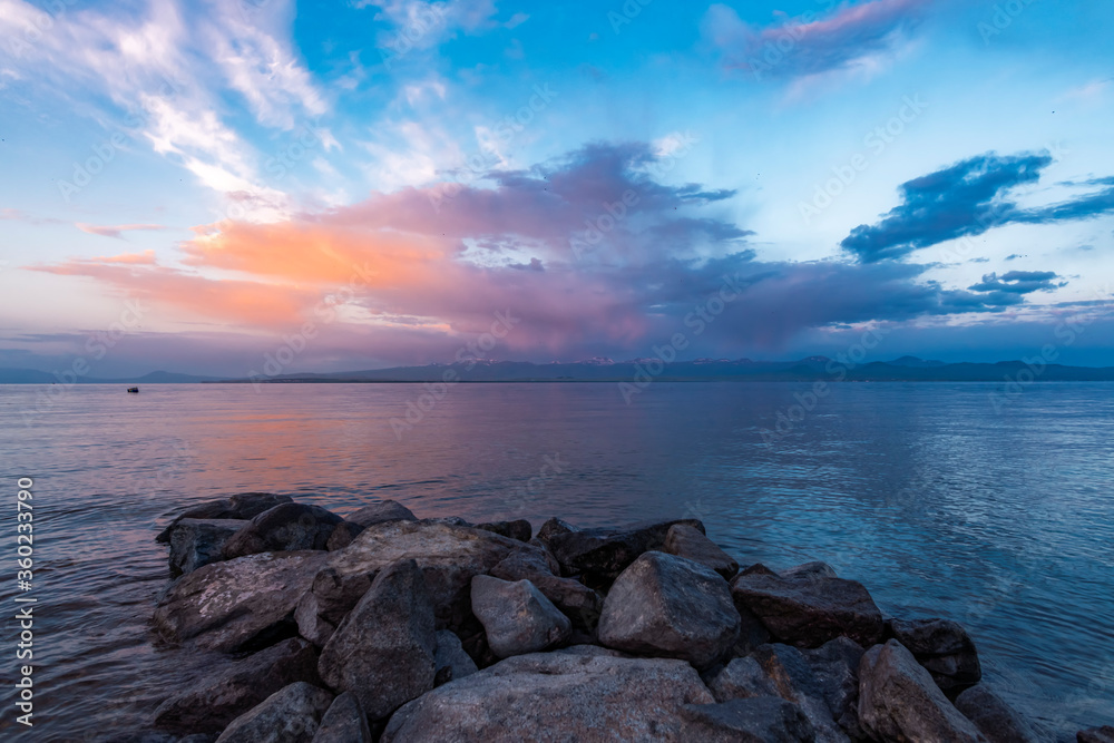 Beautiful sunrise on the lake with colorful clouds and stones on the shore. Armenia Sevan lake Beautiful sunrise on the lake with colorful clouds and stones on the shore. Armenia Sevan lake