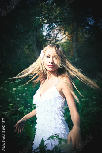 Fairy dancing in the forest. Pretty woman wearied white summer dress is dancing with her hair flying in the air © mettus