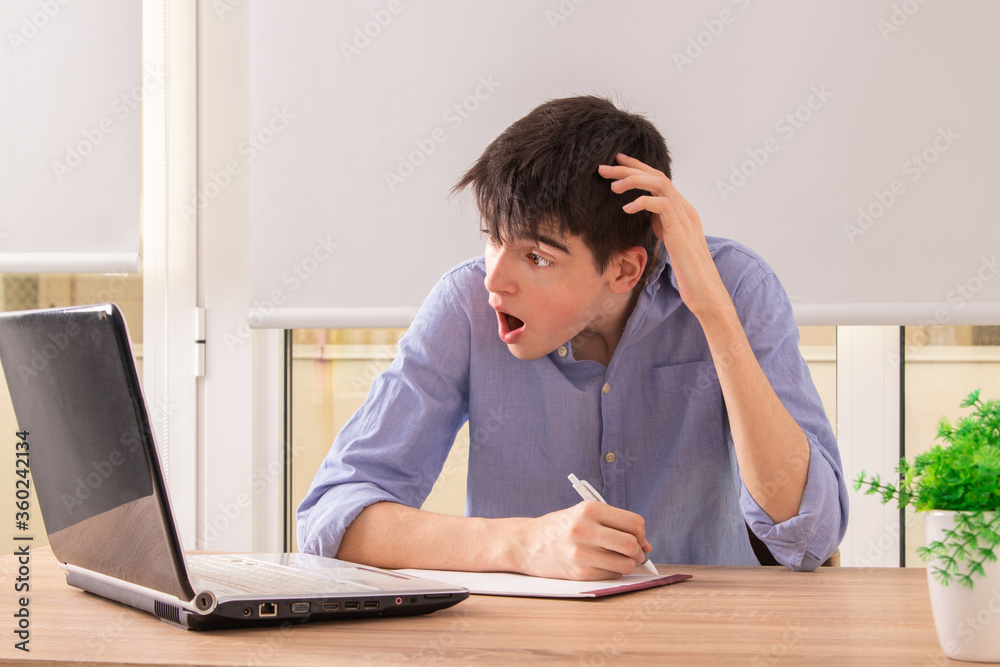 surprised young man studying with computer at home surprised young man studying with computer at home