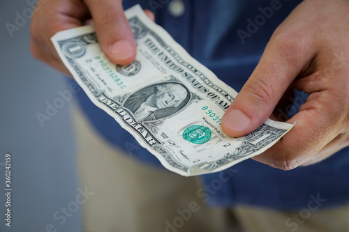 Young men with one dollar bill in his hands, pay with us note, 