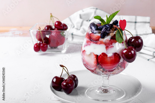 Layered dessert with muesli, berries and yogurt in glass on the white table