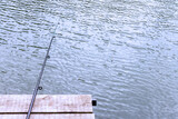 a fishing rod is lying on a wooden pier hanging over the water. concept for the day of the fisherman. Outdoor recreation in summer and autumn.