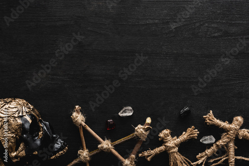 Fotografie top view of voodoo dolls, ancient crystals, pentagram and skull on black