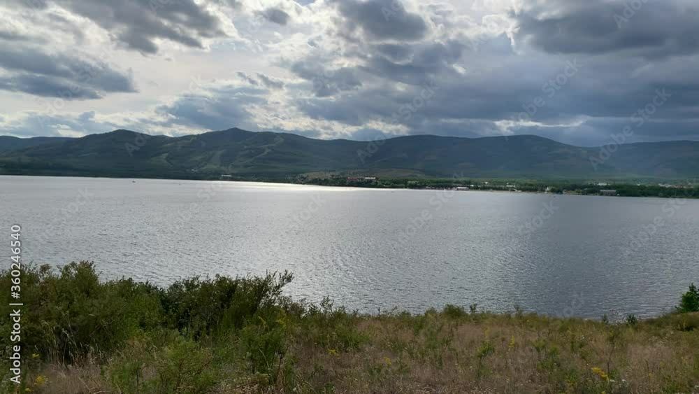Summer landscape. Dramatic sky. Mountain lake. Beautiful blurred background. A large green field with trees and mountains in the background. A body of water with a mountain in the background Summer landscape. Dramatic sky. Mountain lake. Beautiful blurred background. A large green field with trees and mountains in the background. A body of water with a mountain in the background