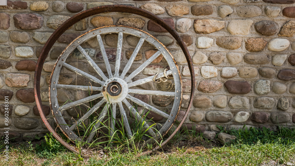 Antique cartwheel and iron rim near the stone wall of the tavern Antique cartwheel and iron rim near the stone wall of the tavern
