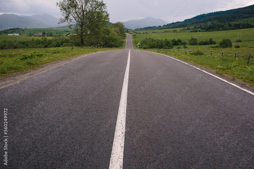 Landscape of asphalt the road is straight in the mountains. Many green trees. Vacation by car. Landscape of asphalt the road is straight in the mountains. Many green trees. Vacation by car.