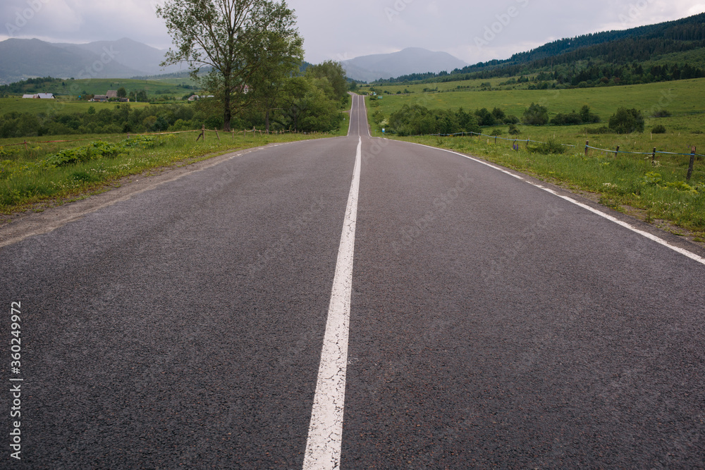 Landscape of asphalt the road is straight in the mountains. Many green trees. Vacation by car. 