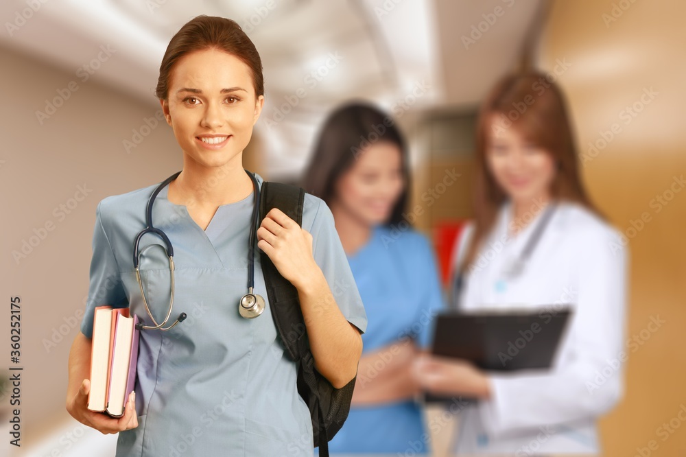 Nurse student with books and stethoscope with blurred hospital interior on background Nurse student with books and stethoscope with blurred hospital interior on background