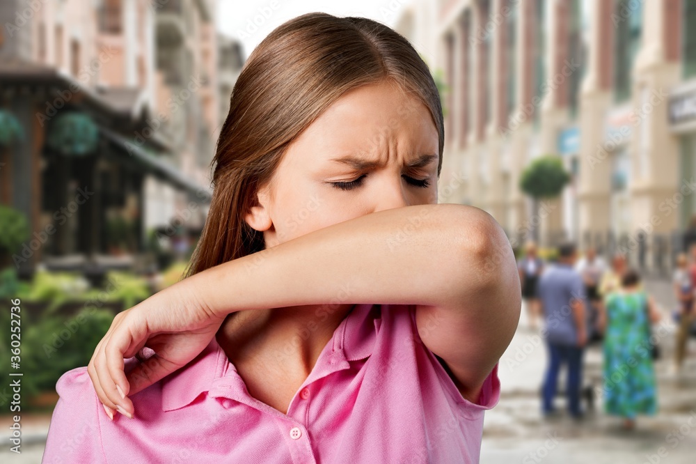 Young woman scratching her nose with elbow on background