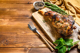 Roasted goat leg with herbs. Farm meat. Wooden background. Top view. Copy space