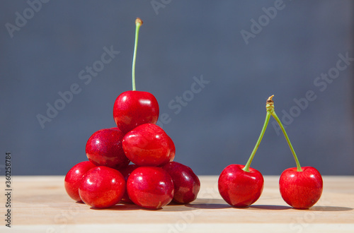 Handful of cherries on a gray background and two berries of a cherry with a tail