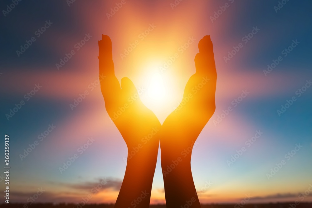 Female hands holding lights of setting sun
