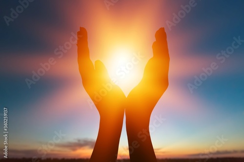 Female hands holding lights of setting sun