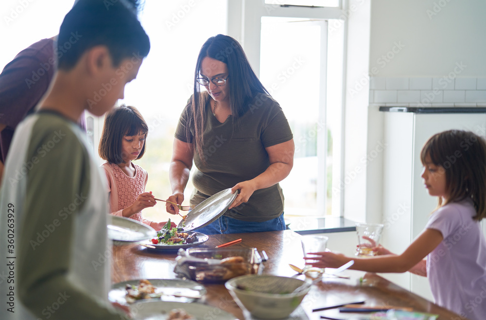 Family clearing food and dishes from dining table Family clearing food and dishes from dining table