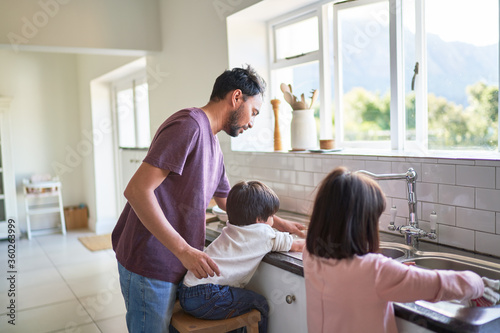 Father and kids doing dishes at kitchen sink