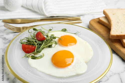 Tasty fried eggs with tomato and sprouts on white marble table, closeup