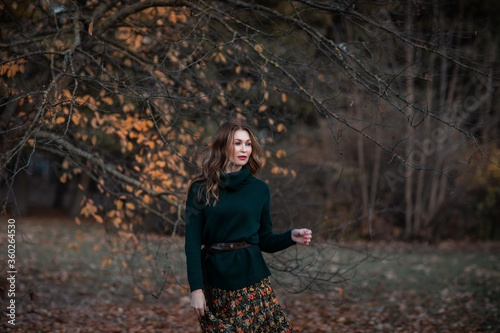Portrait of attractive young brunette woman posing in the autumn park. Copy space.