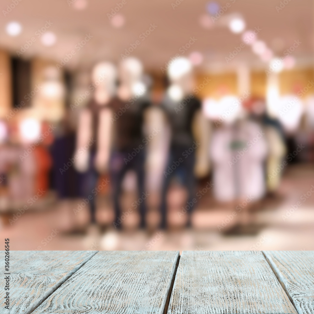 Empty wooden table and blurred view of store with modern clothes Empty wooden table and blurred view of store with modern clothes