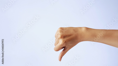 Hand shows a thumbs-down gesture. Close-up of female hand gesture dislike, bad, disapproval isolated on white background