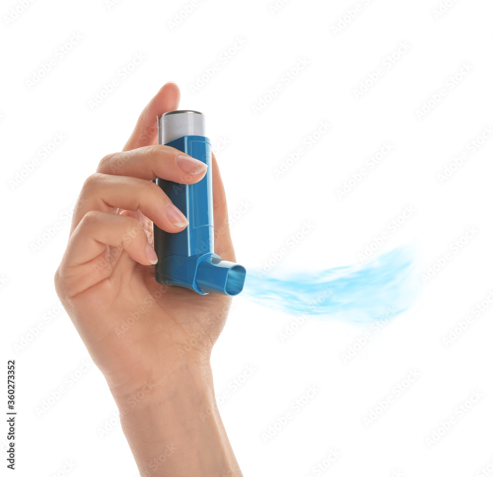 Fototapeta premium Woman holding asthma inhaler with steam on white background, closeup