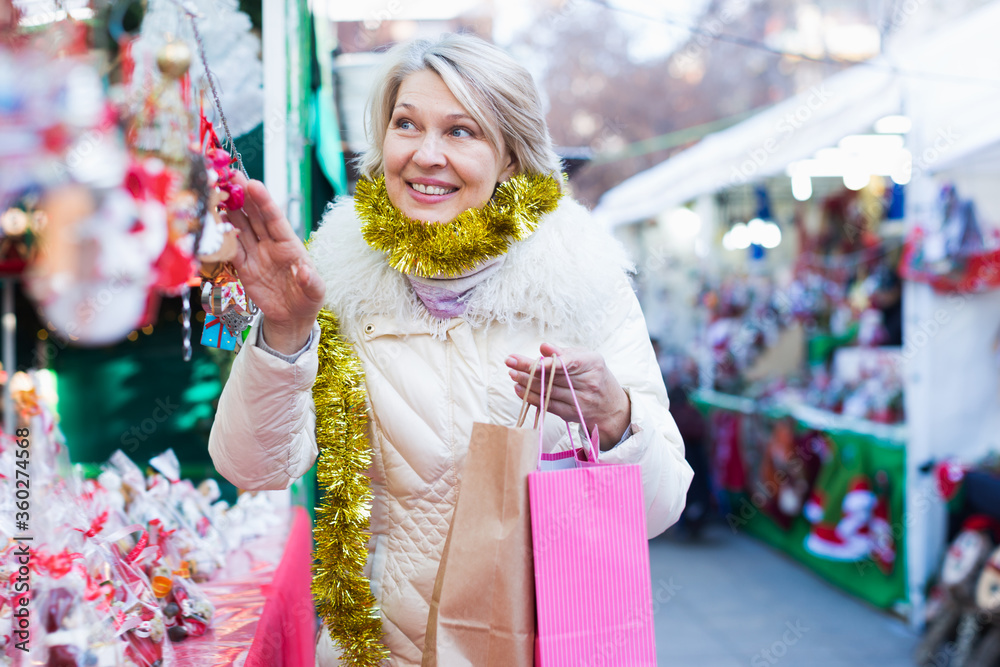 Adult woman is choosing Christmas decorations for house in the market
