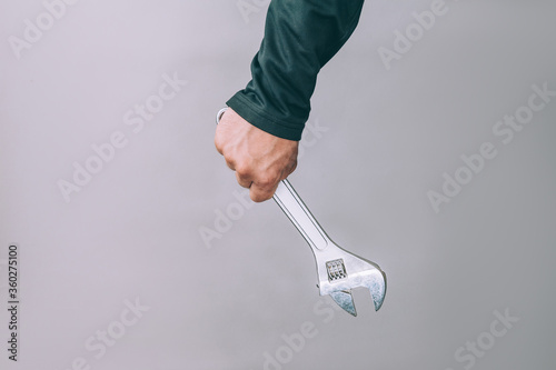 A man holds in his hands a metal wrench for work.