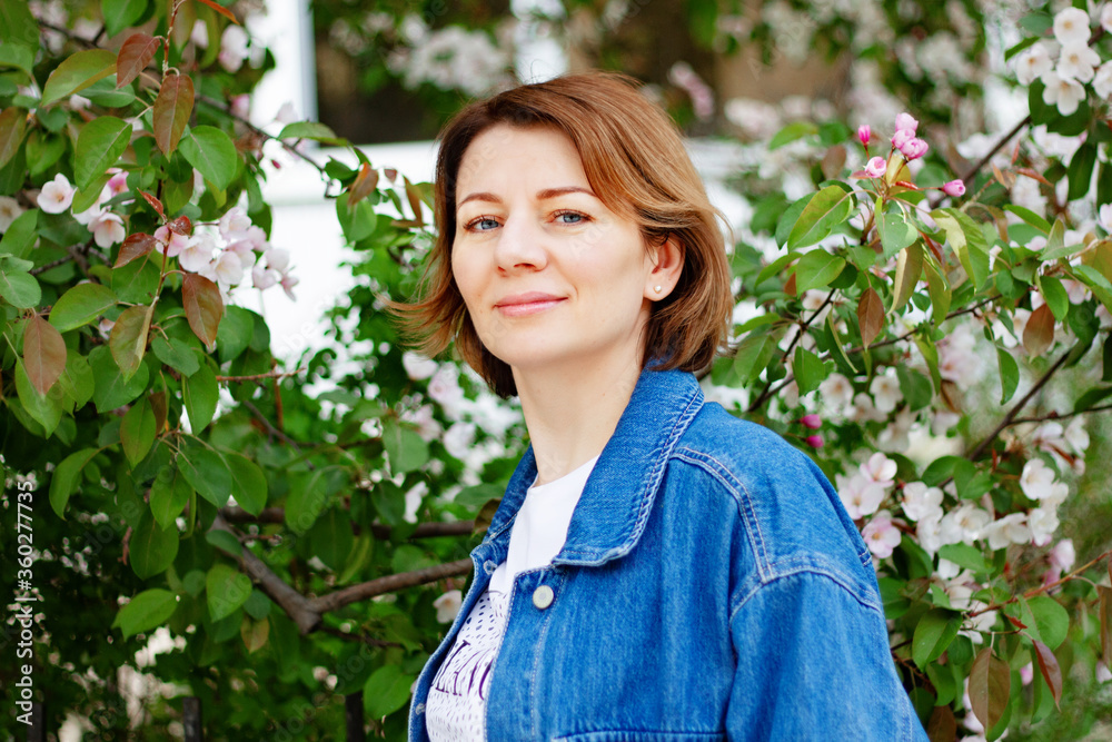Beautiful brown haired woman with blue eyes in an Apple orchard sniffing blooming flowers on a spring day Beautiful brown haired woman with blue eyes in an Apple orchard sniffing blooming flowers on a spring day