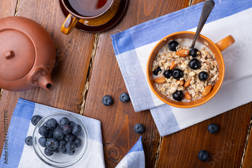 breakfasr with oatmeal porridge with blueberries, fruits, almonds and coconut milk. Healthy and tasty vegan breakfast. top view, flat lay.