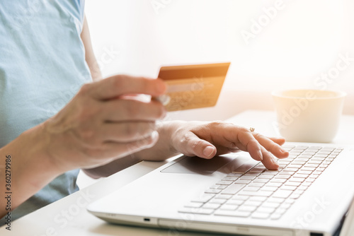 Foto Cropped image of a woman holding a credit card while using a laptop for shopping