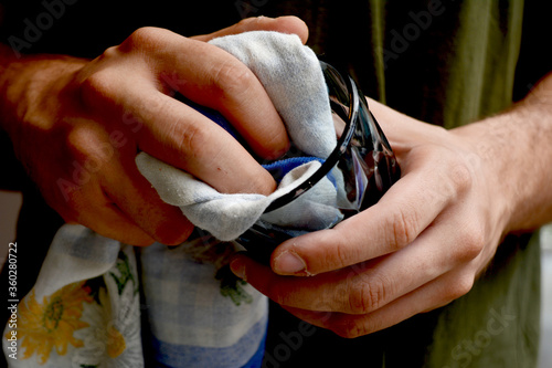 Fényképezés Close up of an adolescent male drying a glass with a kitchen towel wearing casua
