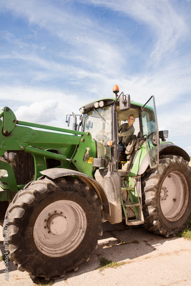 Low angle view of mature woman driving tractor against sky Low angle view of mature woman driving tractor against sky