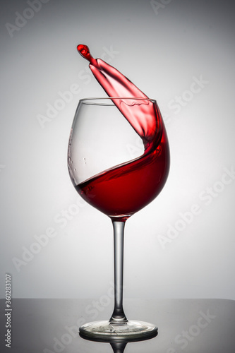 A splash of red wine in a glass on a white background