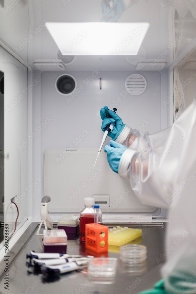 Cropped image of scientist holding pipette over machinery at laboratory Cropped image of scientist holding pipette over machinery at laboratory