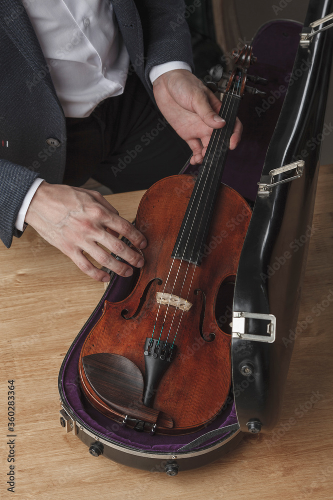 Midsection of man keeping violin in case at table Midsection of man keeping violin in case at table